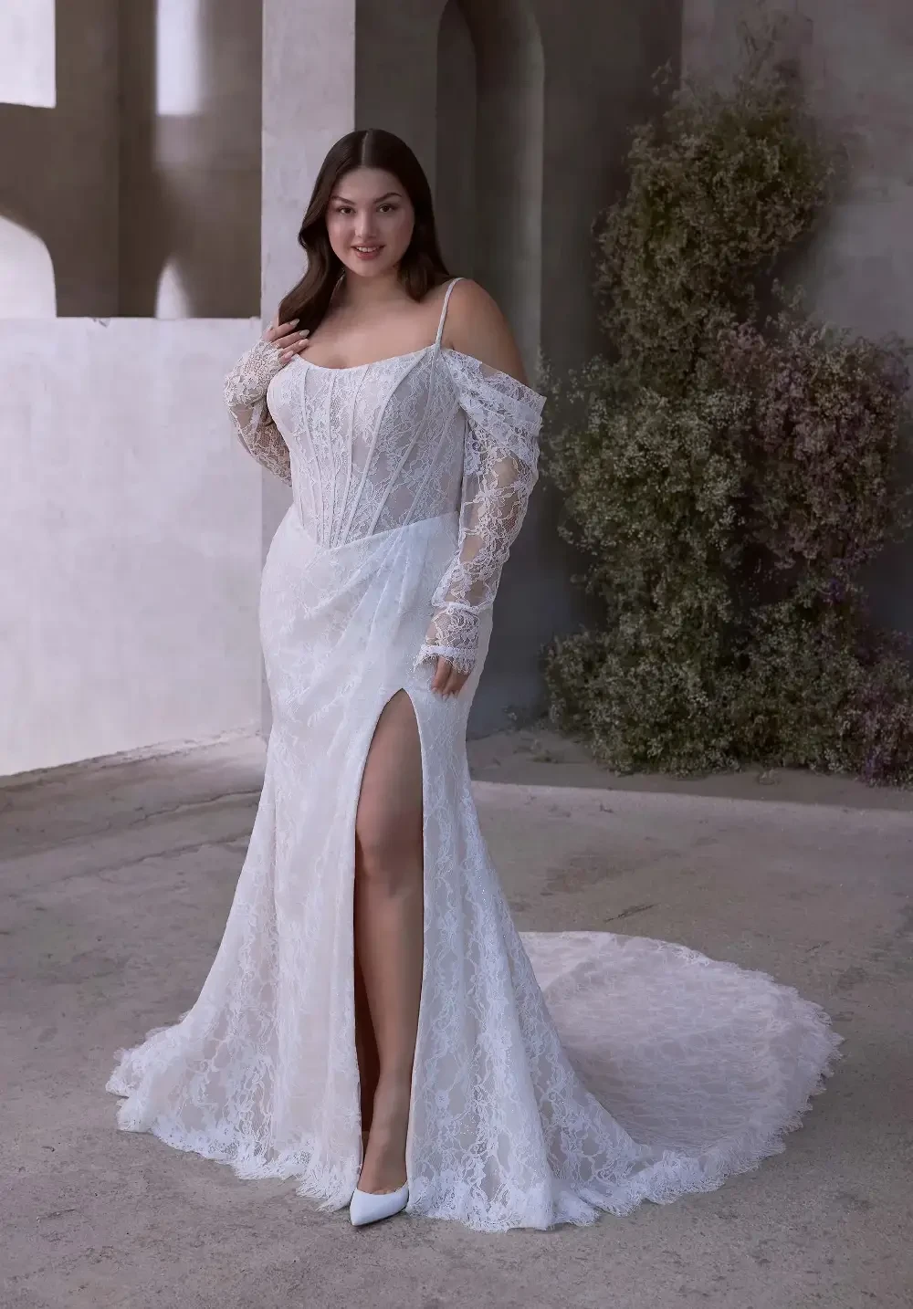 model is wearing a plus size lace off the shoulder bridal gown