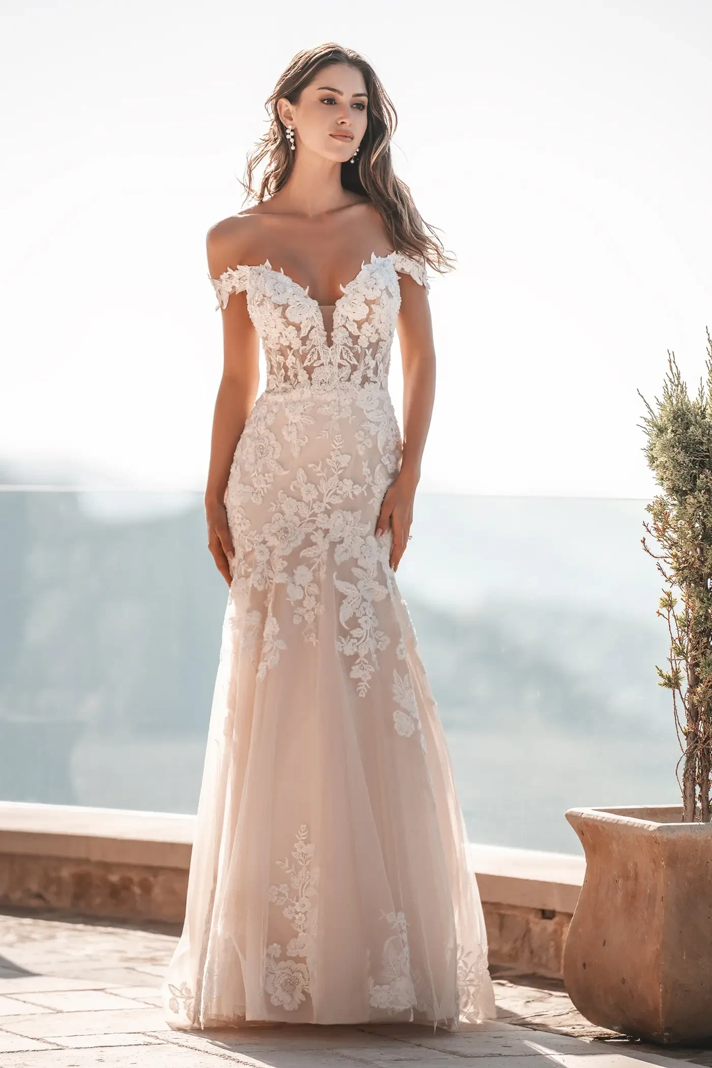 model is wearing an off the shoulder lace bridal gown