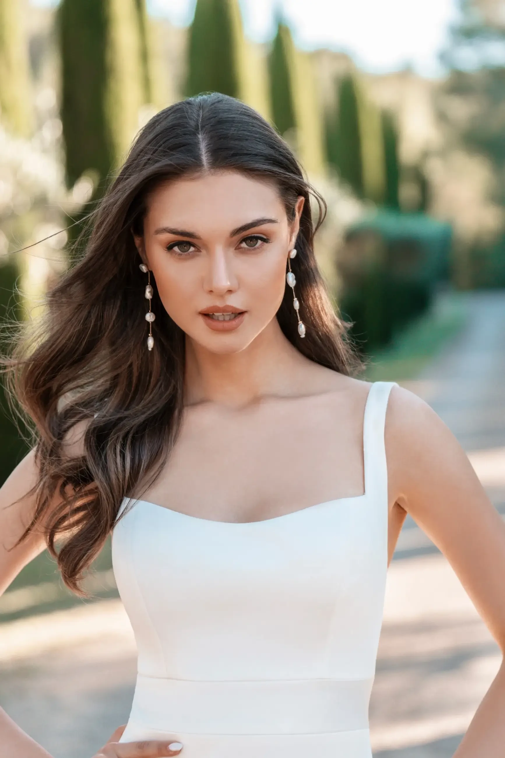 model is wearing a sleeveless sheath wedding dress