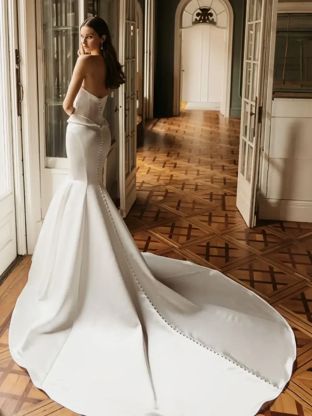 model is wearing a strapless mermaid wedding dress with an open back