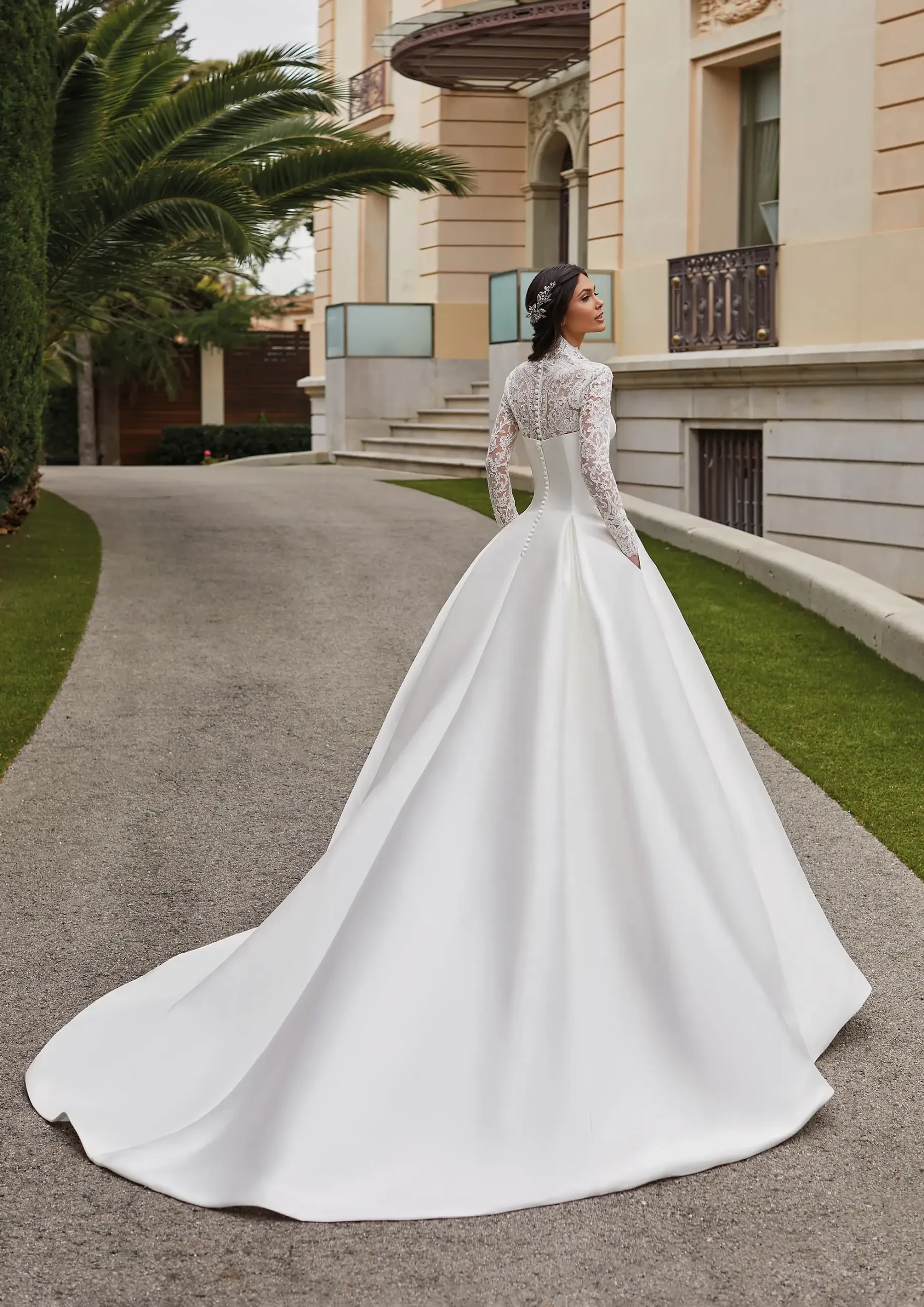 Model is wearing a bold ball gown with a high neckline long sleeve lace overlay on the bust 