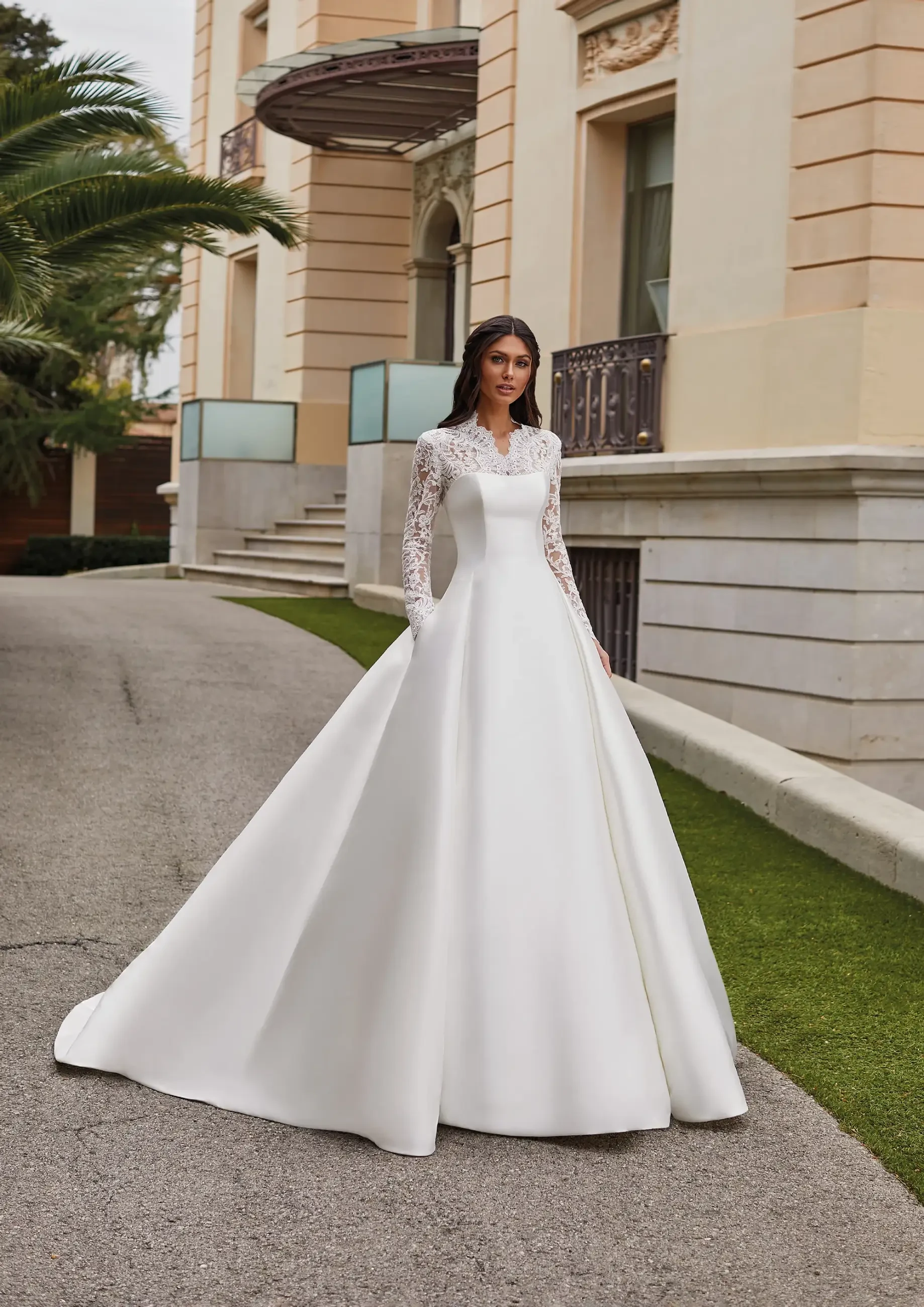 Model is wearing a bold ball gown with a high neckline long sleeve lace overlay on the bust 