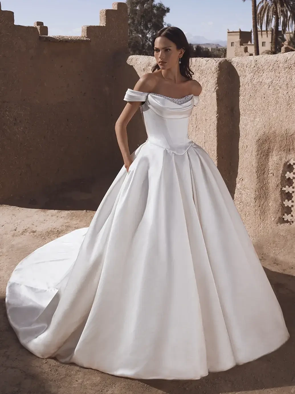 model is wearing an off the shoulder ball gown wedding dress