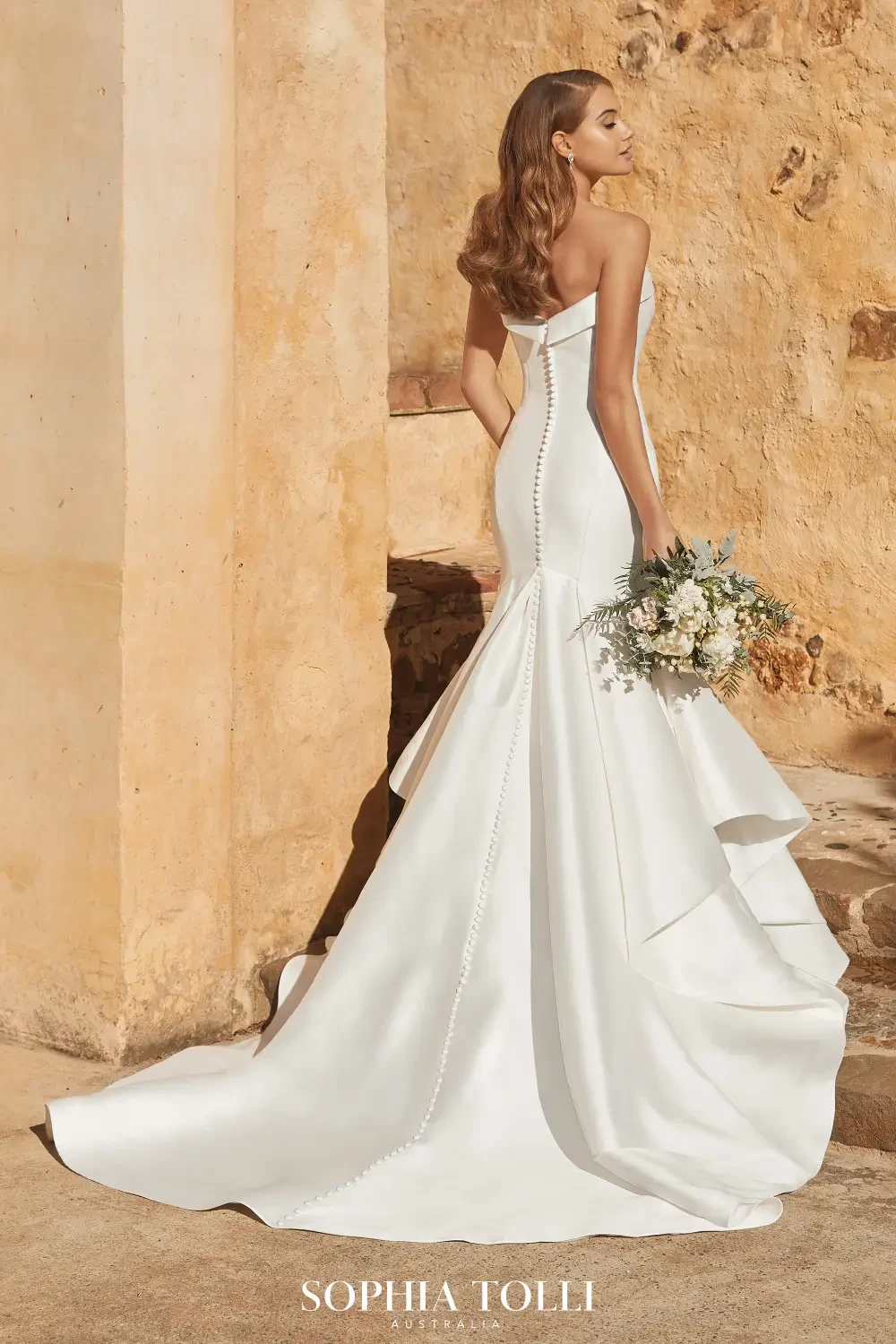 model is wearing a satin strapless fit and flare wedding dress