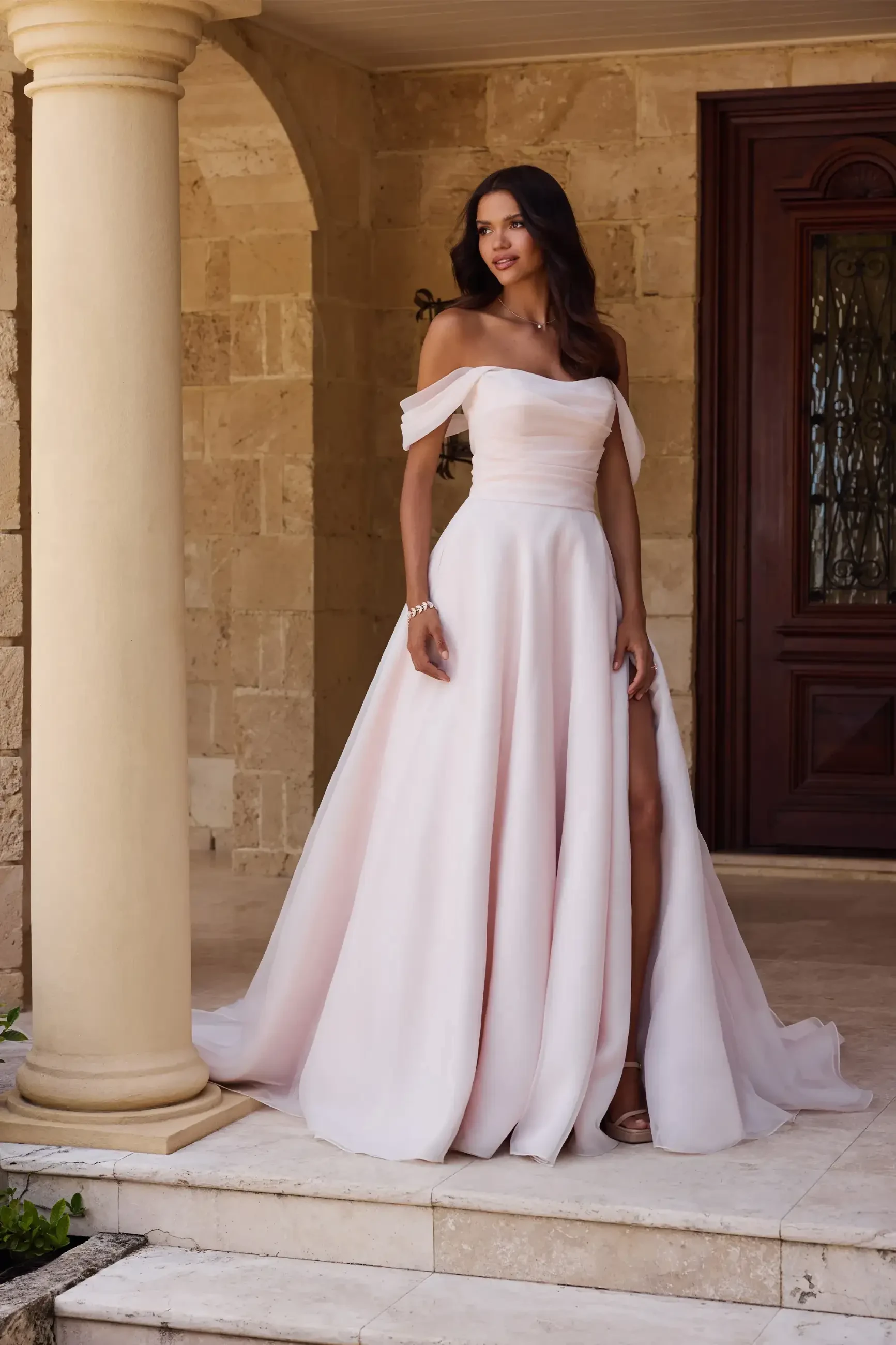 model is wearing an a-line off the shoulder wedding dress