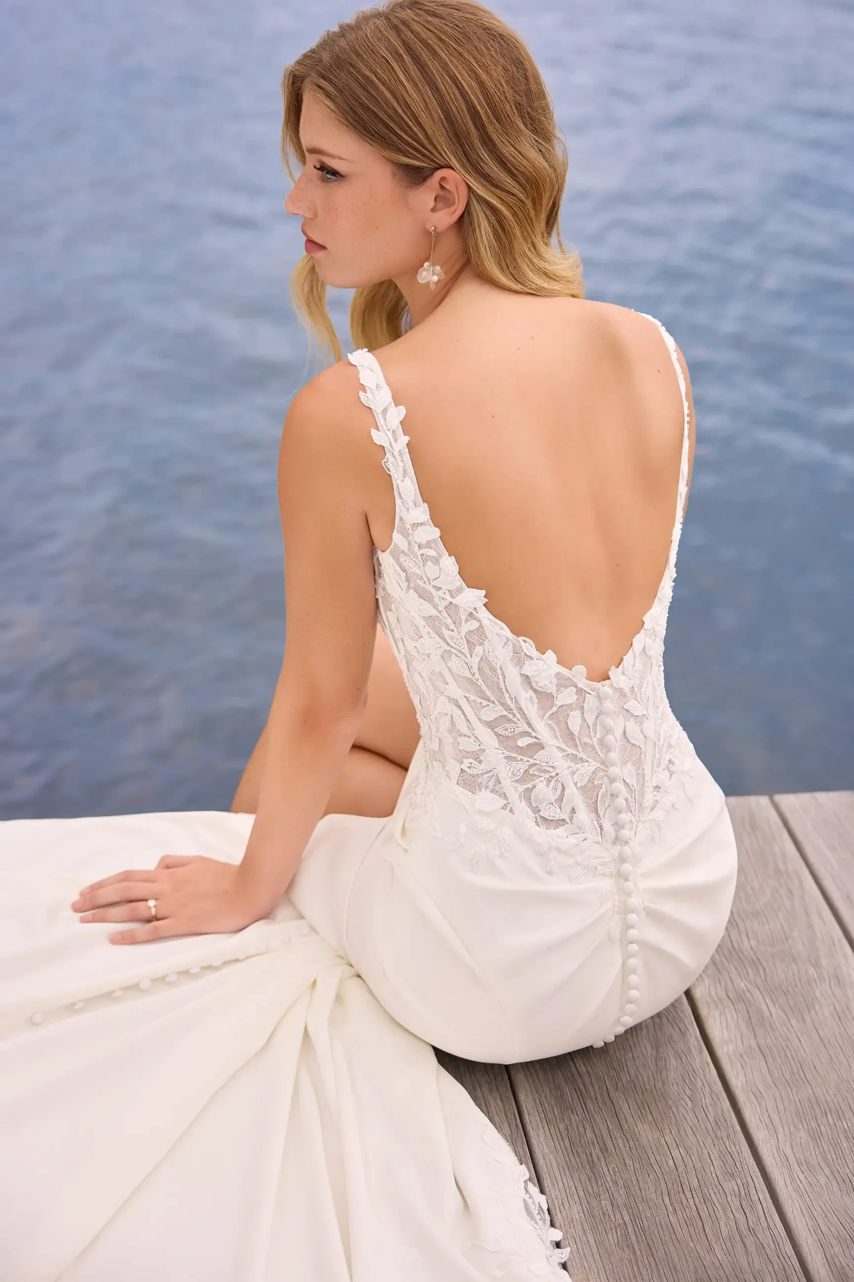 model is wearing a sleeveless fit and flare wedding dress with an open back and beaded bodice